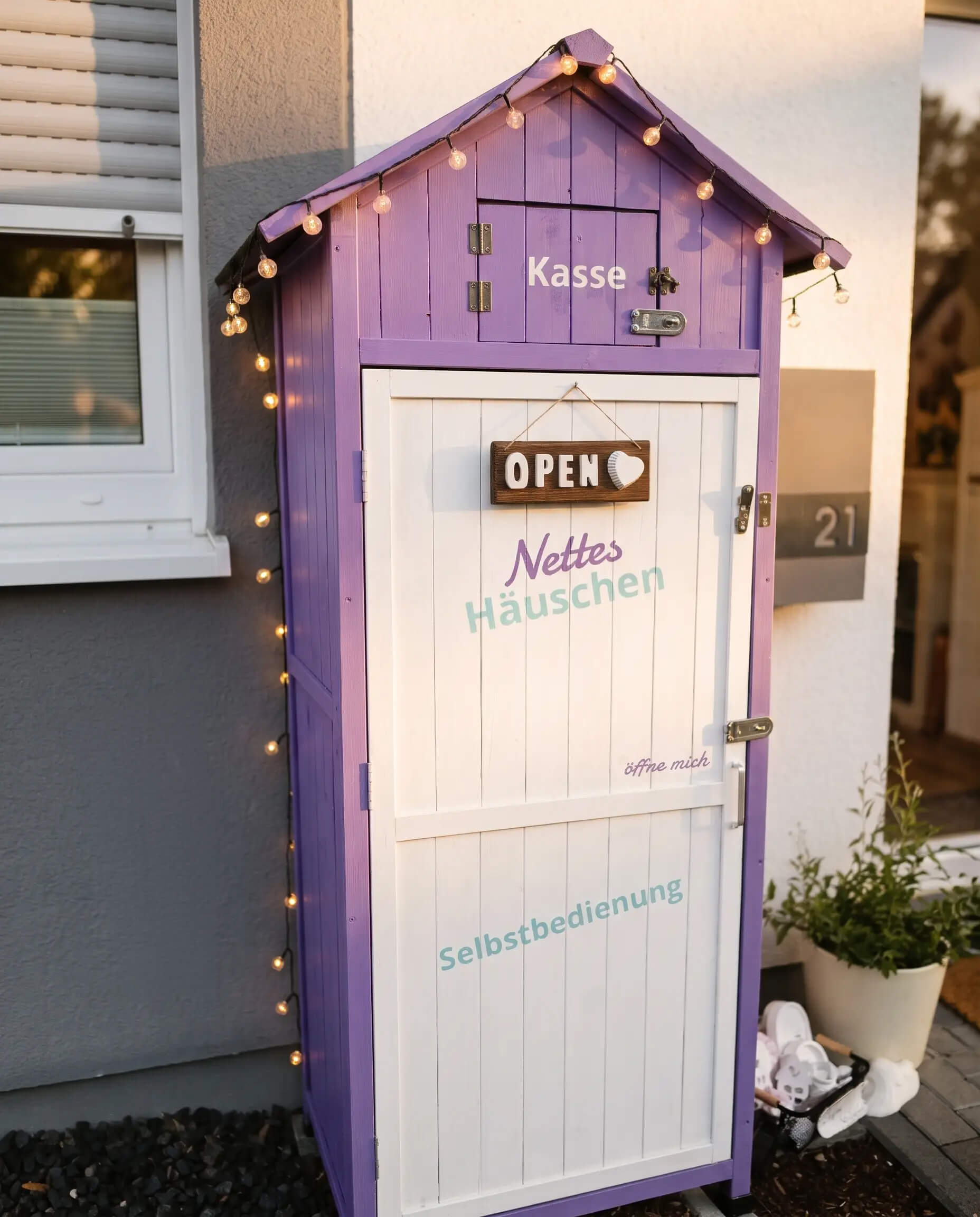 Das lila Selbstbedienungshäuschen mit Lichterkette und Schild Open